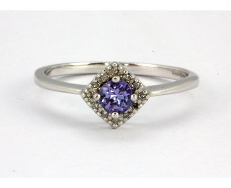 A 9ct white gold halo ring set with a round cut tanzanite surrounded by diamonds, (Q).