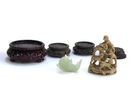 Three Chinese carved hardwood stands, together with one other, a carved soapstone figure group of monkeys, and a carved jade 