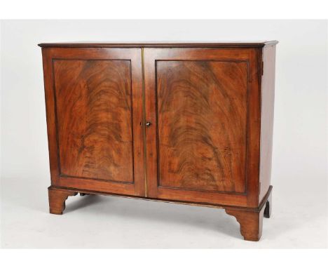 An early 19th century mahogany veneered hall cupboard, with a bevelled top above a pair of broad panelled doors in flamed ven