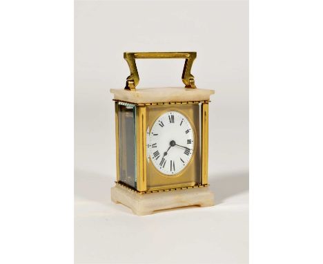 A brass and onyx cased carriage clock, the oval shaped white enamelled dial with black Roman numerals set within a bevelled g