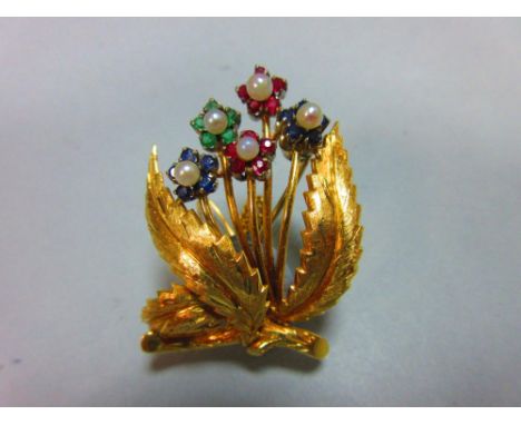 An 18ct gold gemset floral brooch,with realistically modelled and textured branch, leaves and stems, and the five flowerheads