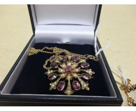 A round amethyst and seed pearl pendant/brooch set with two additional drops stamped 15ct, set on a long unmarked yellow meta