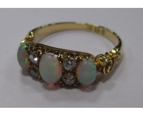 A three stone opal and diamond ring, the three oval opal cabochons interspaced with two small round diamonds to either side o