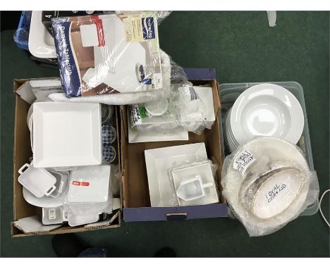 Three boxes containing various ceramic dishes, ramekins, fondue plates, and table clothes.