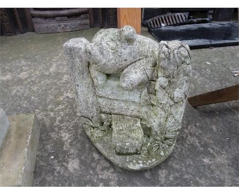 A concrete garden statue of a pig jumping a gate.