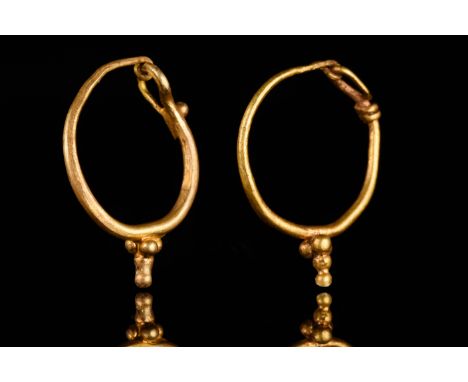 Ca. 200–300 AD. Roman. A matched pair of gold earrings, each comprising a circular hoop with a hook and clasp closure. One of