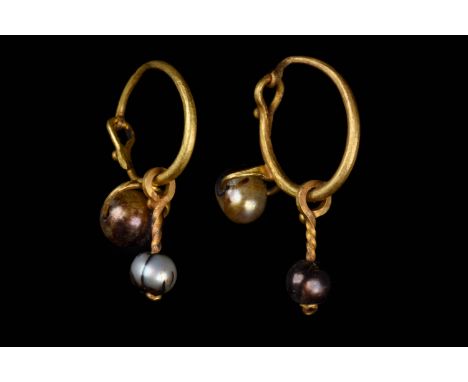 Ca. 600–800 AD. Byzantine. A matched pair of gold earrings, each one comprising a hollow hoop with an attached pearl, a small