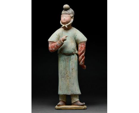 Ca. 618–907. Tang Dynasty. A beautifully modelled terracotta male attendant standing on a flat base. The figure is shown with