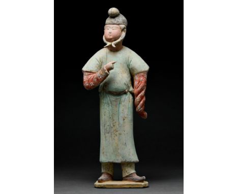 Ca. 618–907. Tang Dynasty. A beautifully modelled terracotta male attendant standing on a flat base. The figure is shown with