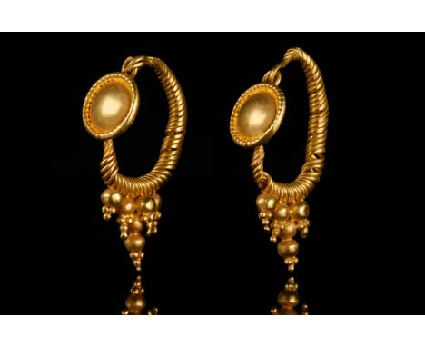 Ca. 100–200 AD. Roman. A beautiful pair of matched gold earrings, each with a hoop of spiral twisted wire, a shield joined to