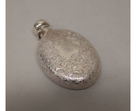 A Victorian silver hinge lidded spirit flask, of oval form, with foliate scroll engraved decoration, monogram engraved within