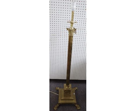 A Victorian brass adjustable standard lamp of Corinthian column form raised on a stepped square base and four lion paw feet. 