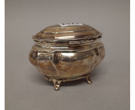 A late Victorian silver hinge lidded tea caddy, of panelled bombe form, raised on four feet, London 1899, weight 178 gms.