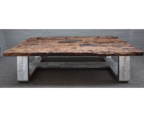 A 20th century coffee table, the planked reclaimed wood top on industrial riveted metal supports, 87cm wide x 152cm long. 