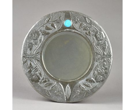 A Liberty style Arts and Crafts pewter wall mirror, circa. 1900, of circular form with bevelled glass relief embossed foliate