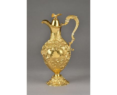 A Victorian silver gilt claret jug, embossed and chased with scrolls, flowers and birds, the hinged lid with a bird of prey f