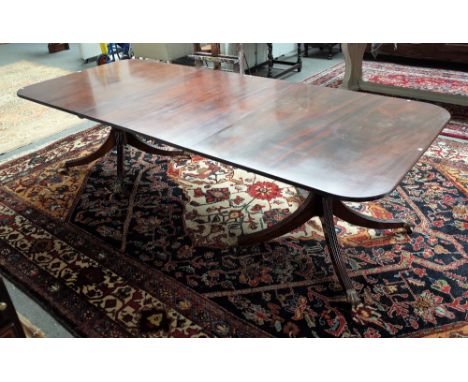 A Regency style mahogany twin pillar extending dining table on eight downswept supports, two extra leaves, 114cm wide x 182cm