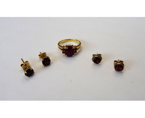 A gold and garnet ring, mounted with an oval carbuncle garnet to the centre, between two pairs of circular cut garnets and tw