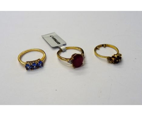 A 9ct gold ring, claw set with a row of three oval cut tanzanites, a 9ct gold ring, claw set with an oval cut treated ruby, b