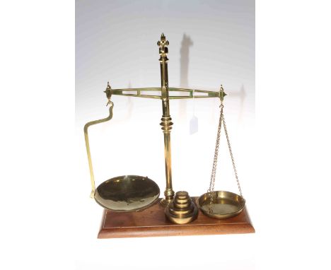 Set of brass balance scales and weights on mahogany plinth.