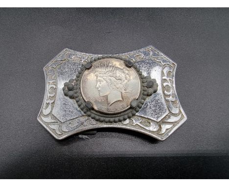 Coins: a US 1928 Liberty head silver dollar, inset to a vintage chromium plated belt buckle. 