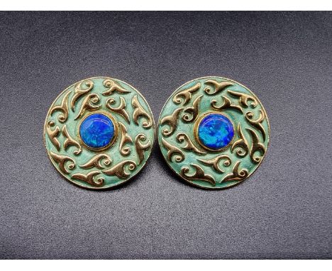 A pair of yellow metal circular ear clips, set central dark opal and decorated green enamel, 32mm diameter. 