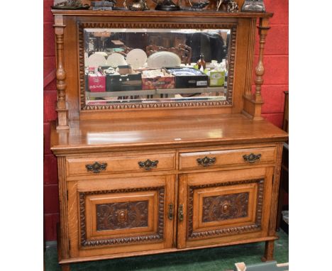 An early 20th century oak sideboard, broken-arch pediment above a shelf and a rectangular bevelled glass mirror flanked by tu