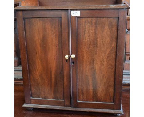 A 20th century mahogany table-top cabinet, moulded top with three quarter gallery above a pair of panel doors enclosing an ad