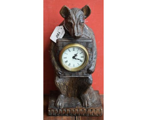 A 20th century Black Forest style bear clock, carved as seated, holding the clock dial to his chest, mechanical manual wind m