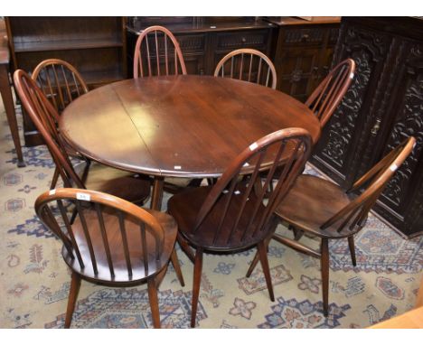 An Ercol elliptical drop leaf dining table, opens to 125cm wide; a set of four conforming Ercol dining chairs; another set of