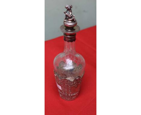 An embossed silver mounted glass liqueur decanter, the stopper with cast silver cherub top, silver hallmarked Chester 1900, o