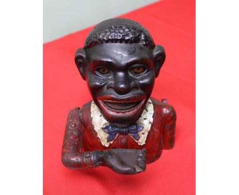 A cast iron money bank, remains of painted decoration, having articulated right arm These items are listed on the basis they 