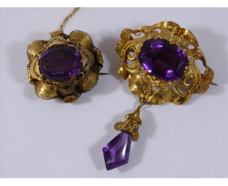 YELLOW METAL FILAGREE AND ENGRAVED BROOCHES EACH SET WITH A LARGE AMETHYST, ONE WITH AMETHYST DROP