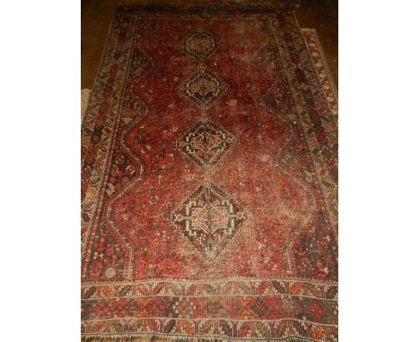 A red, orange and brown Caucasian carpet, having four stepped medallions to centre, on a geometric patterned ground, within g