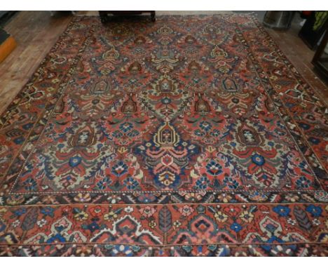 A red ground Bakthiari carpet, decorated with stylised flowers in vases to centre, within floral borders, finged, L: 400cm, W