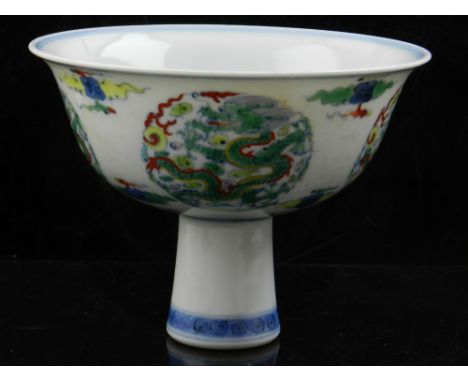 A Chinese doucai porcelain stem bowl, decorated with vignettes of dragons chasing a flaming pearl amongst stylised clouds and