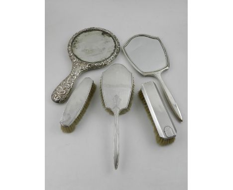 A silver four piece silver dressing table set, having engine turned design to include hand mirror, and three brushes, stamped