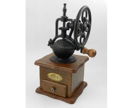 A manual coffee grinder, raised on wooden base, fitted drawer.