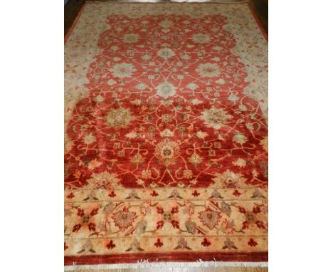 A red ground Ziegler style carpet, overall decorated with scrolling flowers and flowers, within cream ground borders, fringed