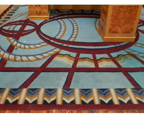 A large foyer carpet, decorated with puce ovals and ribbons on a sky blue ground within a gold, cream and blue chevron border