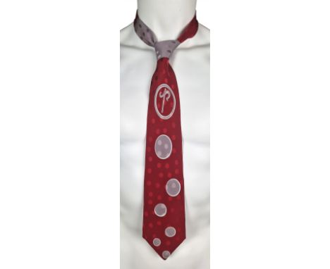 ˑ A red and grey Pashu tie which was previously owned by Freddie Mercury. It features a spotted design.
The tie measures 133.