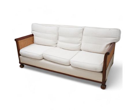 Early 20th century mahogany framed bergère three seat sofa, upholstered back and seat flanked by rolled double-caned arms wit