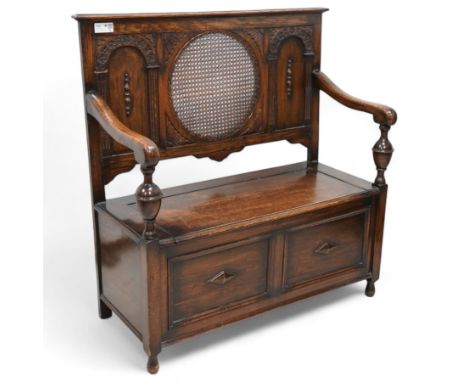 Early 20th century oak hall bench, circular caned back enclosed by panels decorated with flowerhead carved arcades, hinged bo