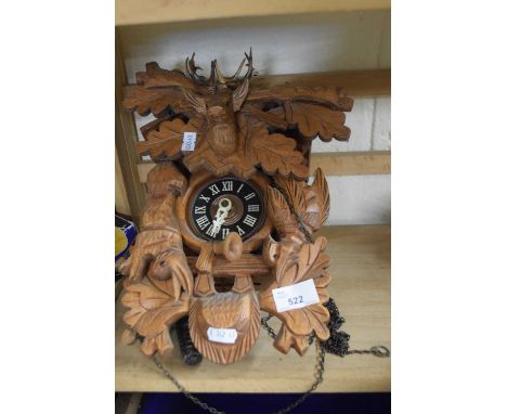 A large modern cuckoo clock with heavily carved face depicting a stags head