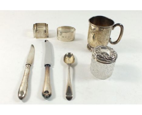 A silver christening mug, silver spoon, two napkin rings and a cut glass silver topped dressing table jar etc. 138g 