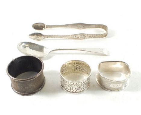 A silver napkin ring with embossed decoration, two other napkin rings and a pair of silver sugar tongs with bright cut decora