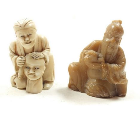 An antique Japanese ivory netsuke in the form of sculptor carving a head, 5.5cm high and a carved soapstone miniature figure 