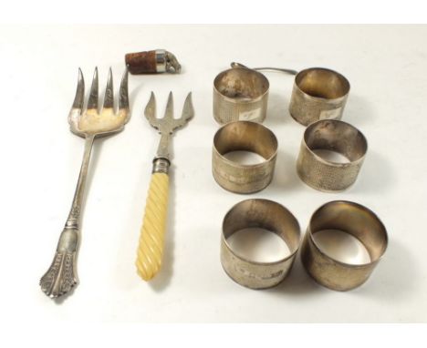 Six silver napkin rings, two silver plated forks, a silver cruet spoon and a white metal frog bottle stopper 