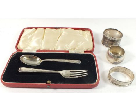 Three individual silver napkin rings and a silver fork and spoon set, gross weight 106g.   Note - one of the napkin rings is 