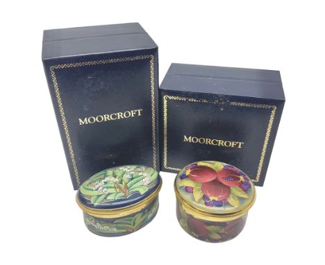 Two Moorcroft enamel boxes, the first example of oval form, decorated with lily of the valley upon a blue ground, the second 
